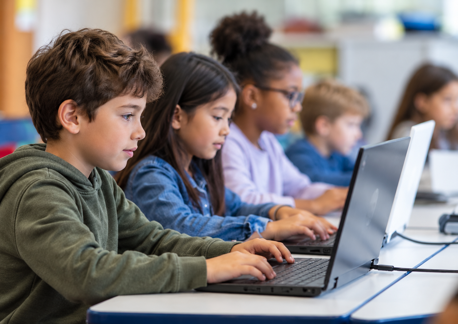 Kinder tippen auf einem Laptop während einer KiDI-Unterrichtsstunde